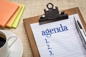 agenda list on clipboard with a pen, coffee and sticky notes against burlap canvas - office abstract | plan hoa meeting