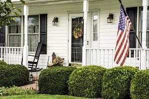 white colonial home decorated for fall with American flag flying from the front porch with rocking chairs | hoa rules and regulations