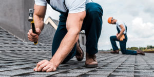 two men repairing house roof | community maintenance checklist